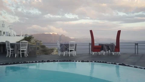 Medium shot of empty poolside restaurant tables on a windy day in Santorini Stock Footage 257672392