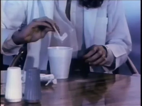 Medium shot of female adding sugar into beverage in disposable coffee cup, 1970s 스톡 동영상 64820245