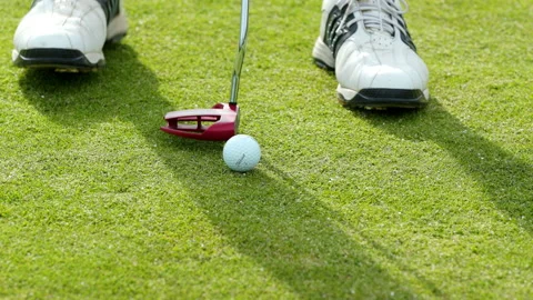 Medium shot of a golfer putting his golf ball on the grass and hitting the golf Stock Footage 163059767