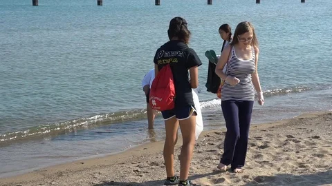 MEDIUM SHOT OF GROUP COLLECTING DEBRIS ON LAKE MICHIGAN BEACH Stock Footage 128333124