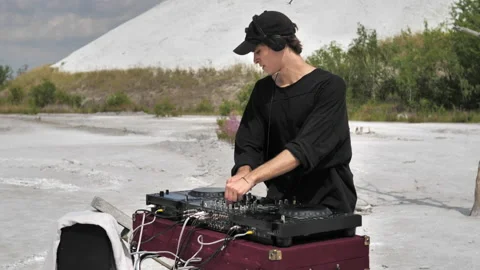 A medium shot of a guy making music at a DJ set in the middle of a white desert Stock Footage 172294324