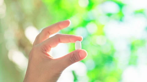 Medium shot hand holding white pill with fingers nature background and amazing Video stock 156245569