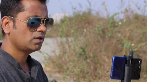 Medium shot of a handsome indian vlogger shooting and recording a video Stock Footage 148425541