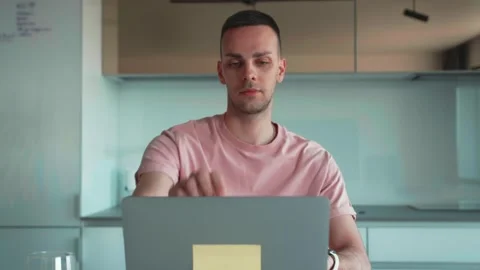 Medium Shot of a Handsome Man Sitting at Wooden Desk Opening and Working on a Stock Footage 241746317
