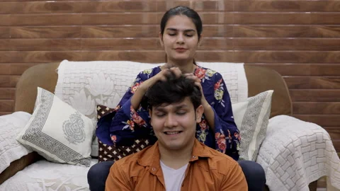 Medium shot of a handsome young guy enjoying a head massage from his sister Stock Footage 156590636