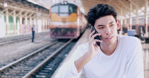 Medium shot of hipster waitng for train in train station, talking on phone, with Stock Footage 106385544