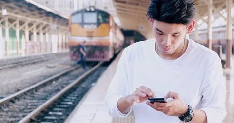 Medium shot of hipster waitng for train in train station, using his phone, Stock Footage 106385785
