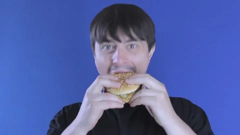 Medium shot hungry guy eats a burger greedily. Unhealthy food Stock Footage 136861891