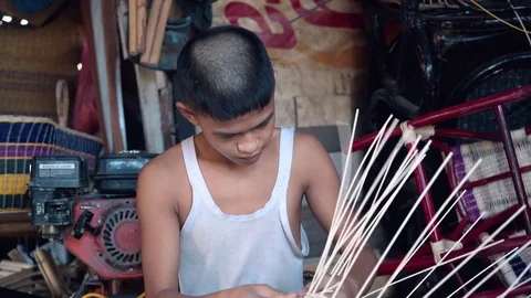 Medium shot of indonesian boy weaving a wicker basket Stock Footage 79142516