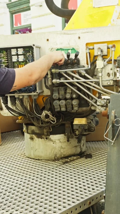Medium shot of a maintenance worker operating hydraulic control levers inside a Stock Footage 338367621