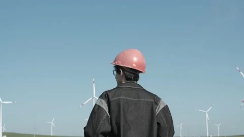 Medium shot of male engineer fixes the helmet in the middle of the windmill Stock Footage 238009332