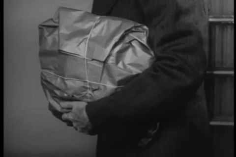 Medium shot of man carrying parcel tied with string, 1940s Stockbeeldmateriaal 35328034