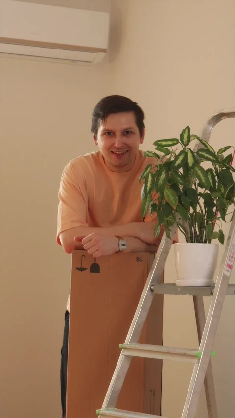 Medium shot of man carrying stack of cardboard boxes into room Stock Footage 346396442
