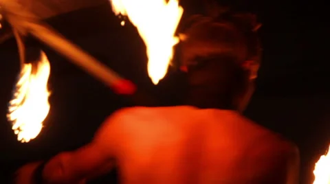 MEDIUM SHOT. Man doing fire juggling in the beach in front to the sea at night. Stock Footage 49757377