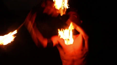 MEDIUM SHOT. Man doing fire juggling in the beach in front to the sea at night. Stock-Footage 49758632