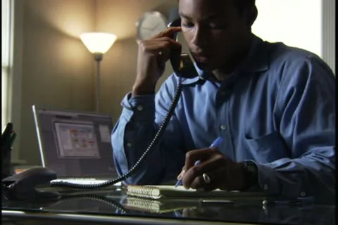 Medium shot of a man as he gets information over the phone and works in his home Stock Footage 11671202