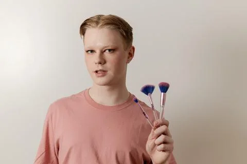 A Medium shot of a Man Holding Makeup Brush Posing with Finished Look Stock Photos