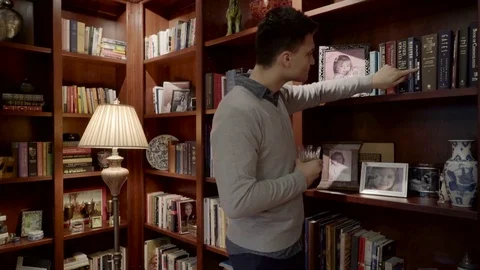Medium shot of a man looking for a book on a shelf 動画素材 73111259