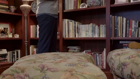 Medium shot of a man looking for a book on a shelf 動画素材 73114055