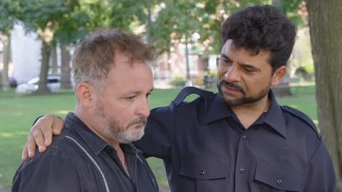 Medium Shot - A man offers advice and counsel to a friend outside at a park - Stock Footage 124911728