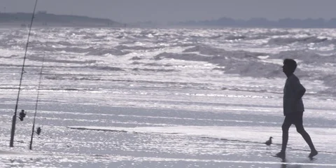 Medium shot of man picking up his fishing rod on the beach Stock Footage 103485962