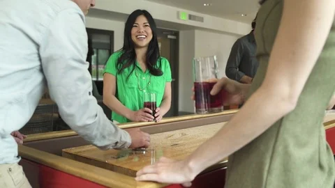 Medium shot of man playing shuffleboard with friends Stock Footage 76539189