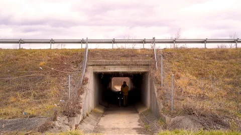 Medium shot of man pushing a bicycle inside of a tunnel, Croatia. Stock Footage 127220232