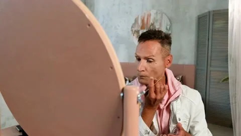 Medium Shot. Man is putting makeup sitting at home looking at the mirror Stock Footage 161833557