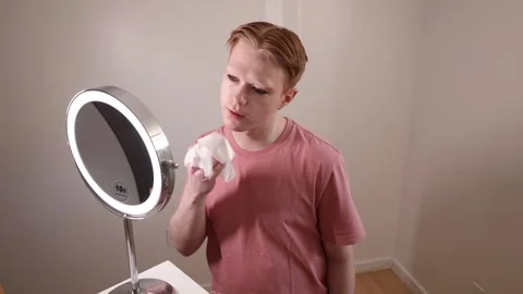 A Medium Shot of a Man Removing Makeup with Wipe in Front of Mirror Stock Footage 310152437