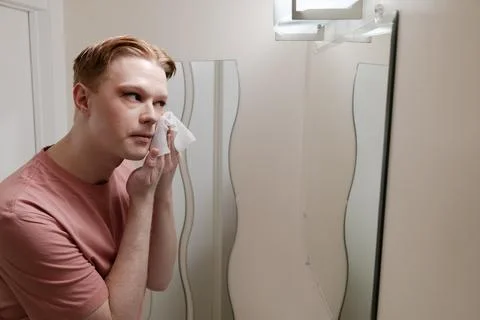 A Medium Shot of a Man Removing Makeup with Wipe in Front of Mirror Stock Photos