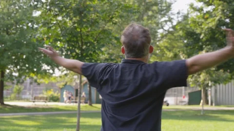 Medium Shot of a man spinning in a park with their arms outstretched - shot on Stock Footage 124909710