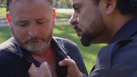 Medium shot - A man squirms about as another man holds his collar and yells in Stock Footage 124910757