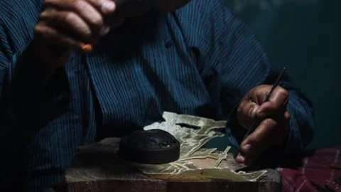 Medium shot master craftsman using wooden hammer and metal punch tool to ca.. Stock Footage 344644949