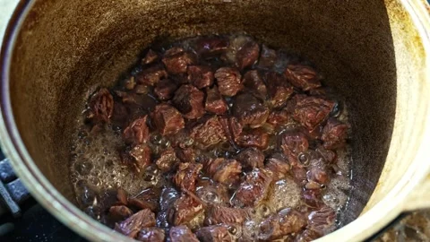 Medium shot meat cooking in kazan cauldron, hand stirring with skimmer spoon Stockbeeldmateriaal 316201630