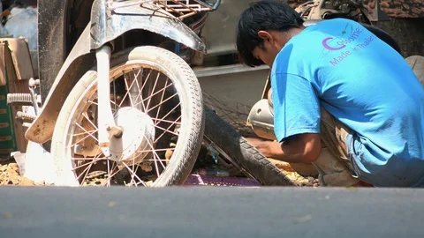 Medium Shot of Mechanic Crouching at Roadside Working on Customers Stock Footage 126670125