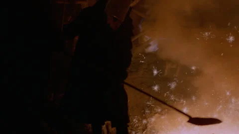 Medium shot of men in protective clothing tending to a steel furnace Stock Footage 312273473