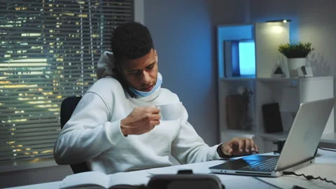 Medium shot of Mixed-race man working on computer, speaking by smartphone and Stock Footage 155766852