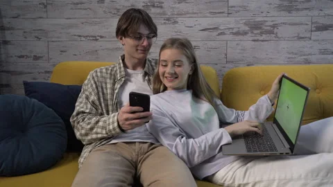 Medium shot A modern young couple on the couch, using gadgets Video stock 259331855
