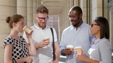 Medium shot of multiethnic colleagues drinking takeaway coffee and talking Stock Footage 157380761