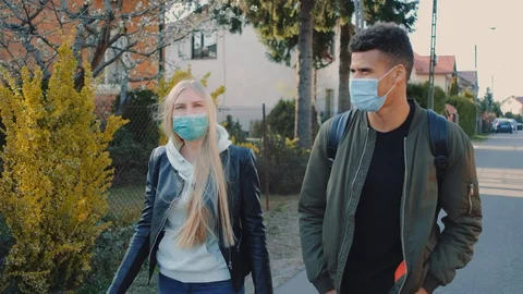 Medium shot of Multiethnic man and woman in medical masks walking down the Stock Footage 129374831