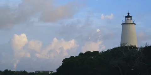 Medium shot of Ocracoke lighthouse and green trees at sunset Stock Footage 103490555