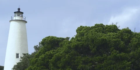 Medium shot of Ocracoke lighthouse surrounded with green trees Stock Footage 103490424