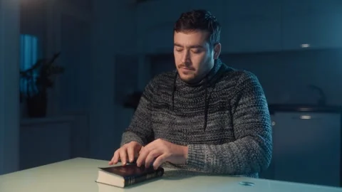Medium Shot One Man Closing Bible And Praying In Dim Kitchen Night Stock Footage 333270815