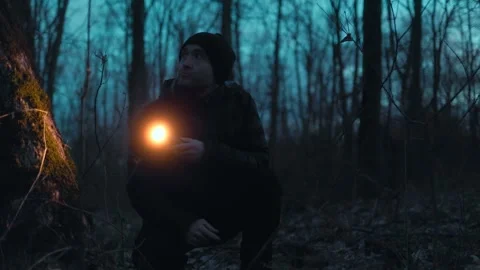 Medium Shot One Man Crouching In Dark Forest With Flashlight lifestyle Vídeo Stock 334002242