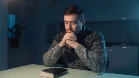 Medium Shot One Man Praying With Hands Clasped Over Bible At Night Stock Footage 333270814