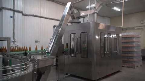 Medium shot of orange-colored juice bottling line Stock Footage 163892298