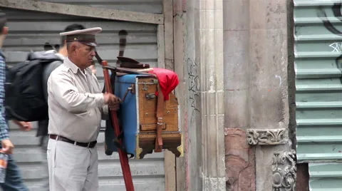 MEDIUM SHOT. Organ grinder, playing the organ in the street. Stock Footage 41131735