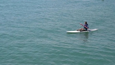 MEDIUM SHOT OF PADDLE BOARDER CROSSING THE FRAME Stock Footage 106124939