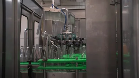 Medium shot pan of bottling line washing, filling with juice and capping bottles Stock Footage 163947766