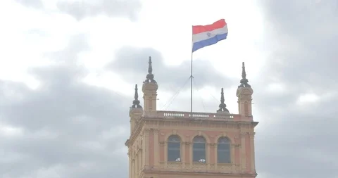 Medium shot of Paraguayan flag waving above Palacio Los Lopez in Asuncion Stock Footage 92777573